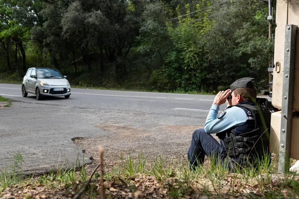 Gendarme utilisant des jumelles lors d'un exercice de surveillance routière pendant un entraînement militaire matinal