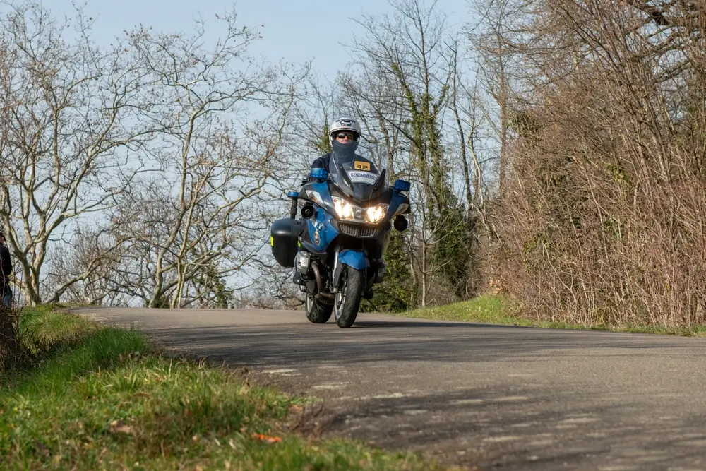 Gendarme à moto patrouillant sur route de campagne, sécurité routière et surveillance du territoire