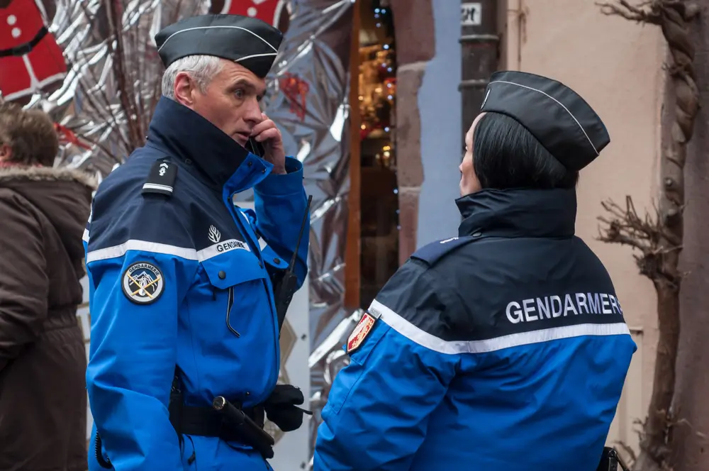 Deux gendarmes français en uniforme bleu patrouillant dans un village rural en hiver