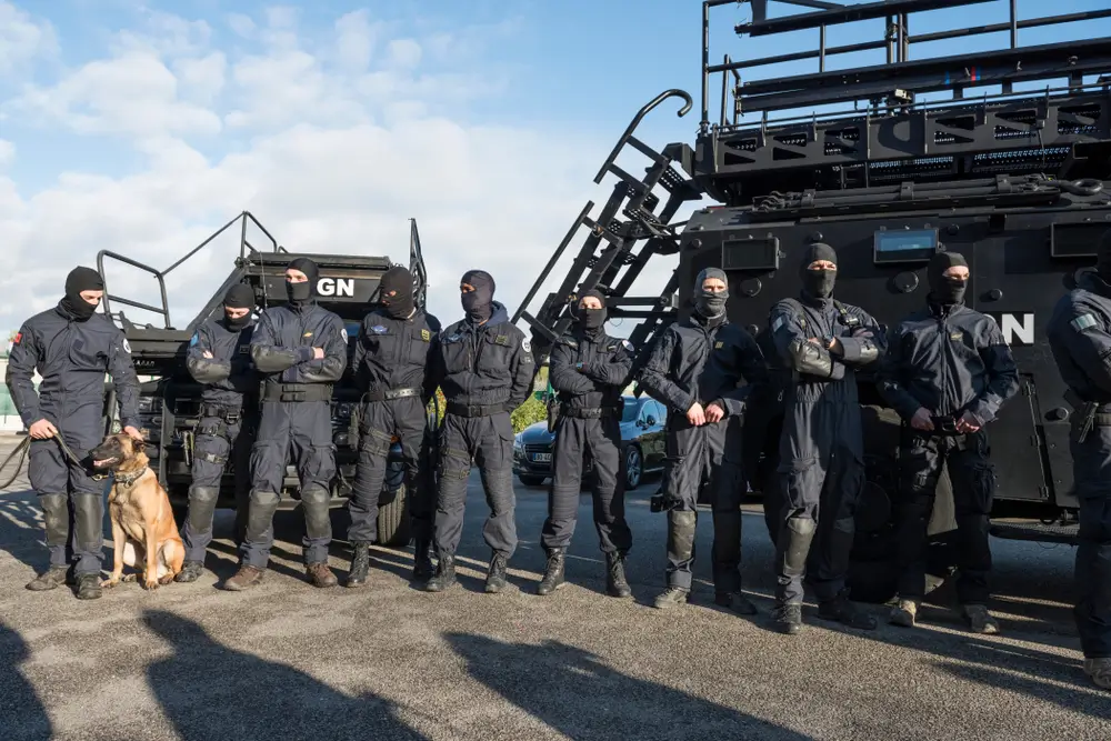 Gendarmes en uniforme d'intervention de la gendarmerie nationale devant un véhicule blindé tactique.
