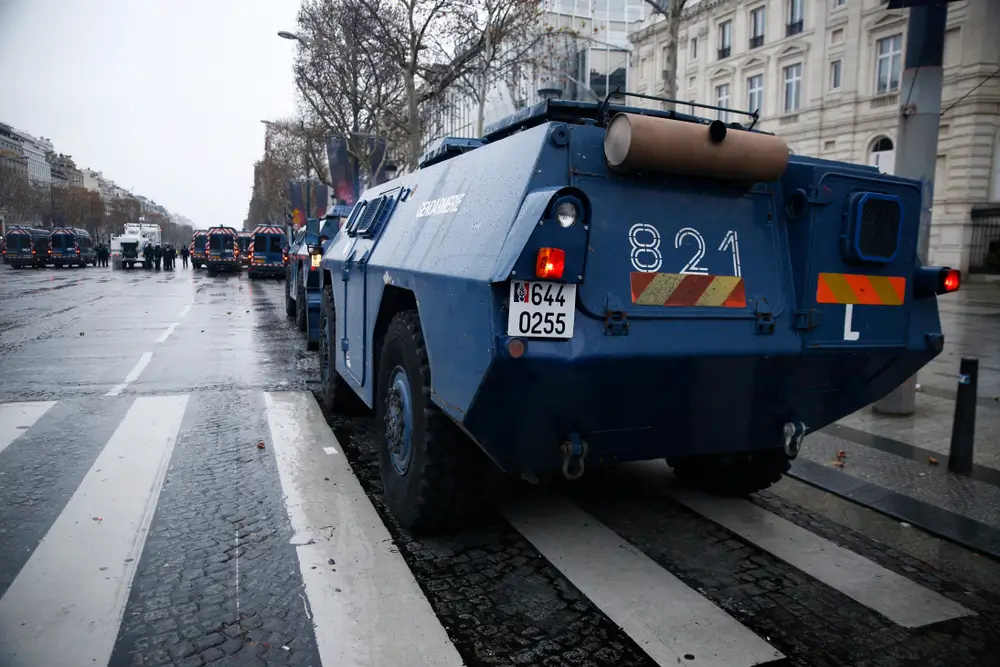 Véhicule blindé de la gendarmerie mobile stationné sur une avenue pavée lors d'une opération de maintien de l'ordre.