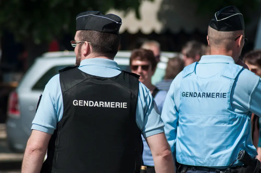 Deux gendarmes en uniforme vus de dos lors d'une patrouille pédestre de sécurisation dans un village.