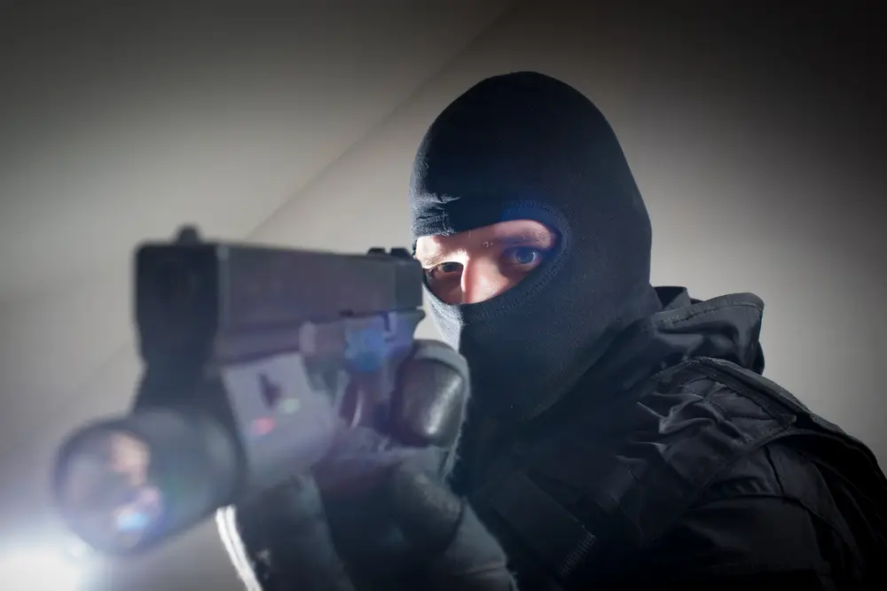 Membre du GIGN cagoulé visant avec un pistolet de poing tactique muni d'une lampe, armement des forces spéciales.