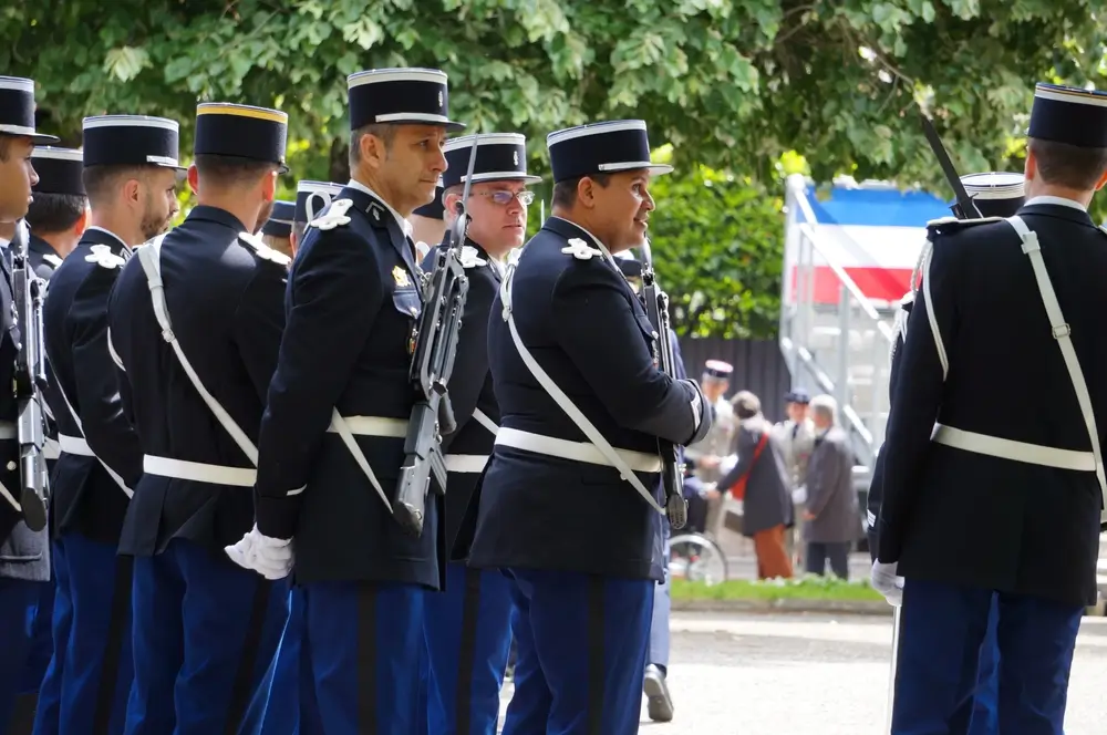 Gendarmes en uniforme de cérémonie alignés lors d'un rassemblement officiel marquant leur évolution de carrière.