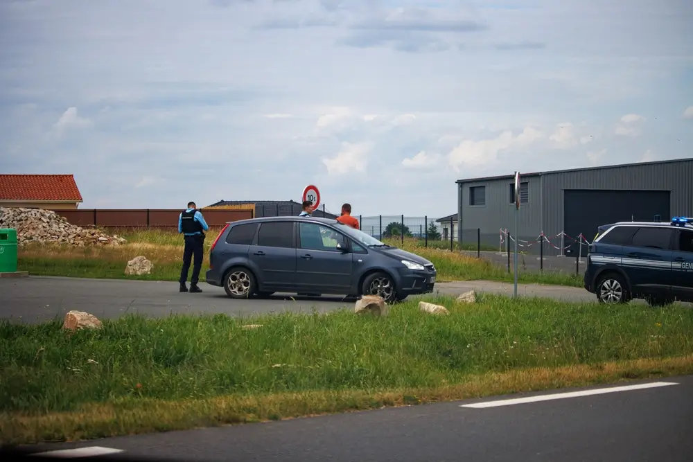 Deux gendarmes en patrouille effectuent un contrôle routier d'un automobiliste à côté de leur véhicule de service.