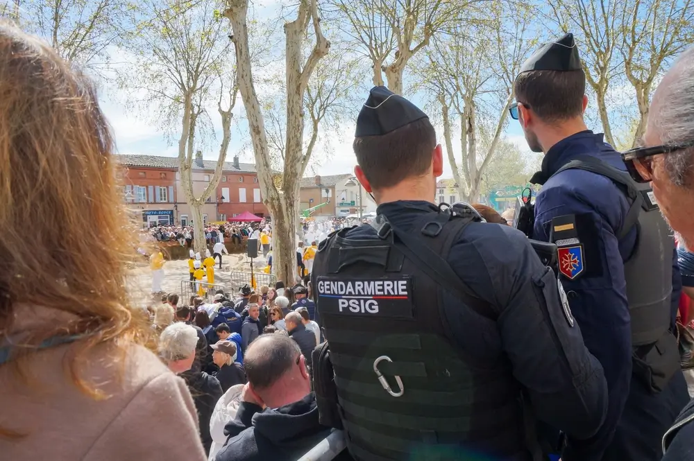 Deux gendarmes du PSIG en patrouille de dos sécurisant un événement public bondé sur une place de village.