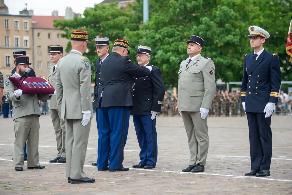 Officier général remettant un galon à un gendarme en uniforme lors d'une cérémonie militaire de promotion.
