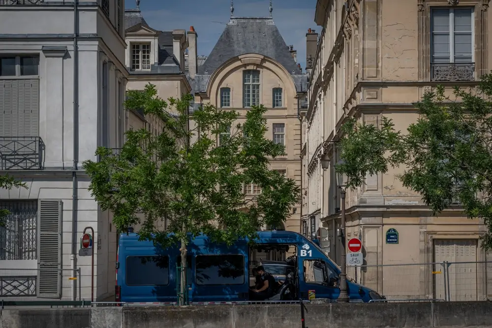 Gendarme en uniforme en patrouille dans un fourgon bleu de la gendarmerie nationale en milieu urbain.