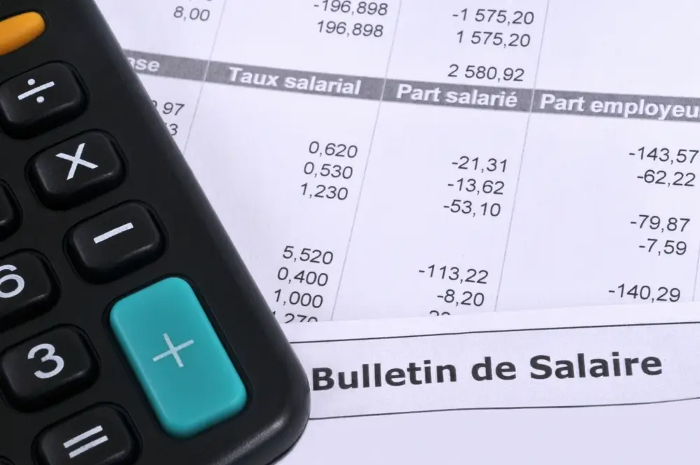 Calculatrice posée sur un bulletin de salaire illustrant les primes et la rémunération d'un gendarme débutant.