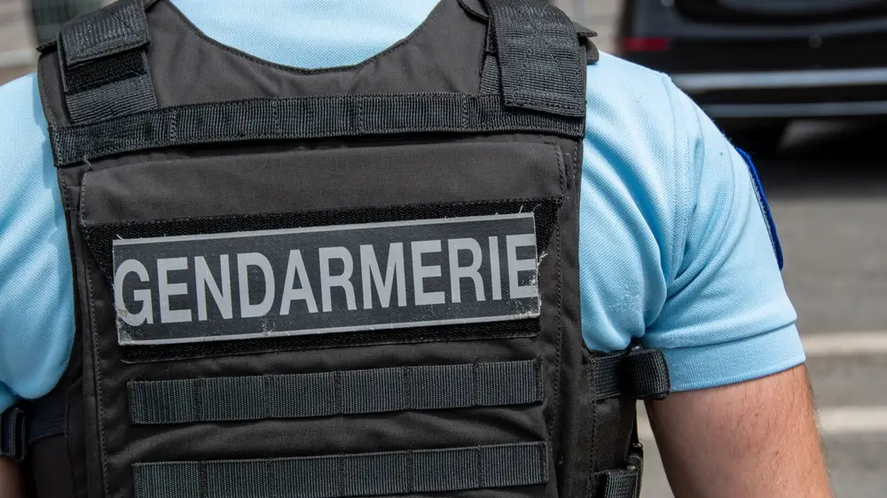 Gendarme de dos portant un gilet tactique noir marqué Gendarmerie lors d'une patrouille de contrôle routier.
