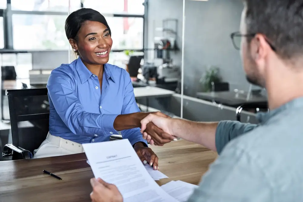 Poignée de main lors d'un entretien d'embauche pour une reconversion professionnelle réussie dans le secteur privé.