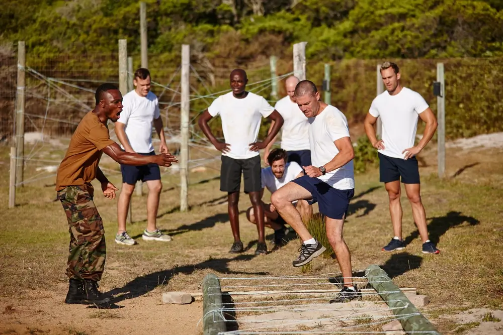 Un gendarme en formation franchit un obstacle au sol sous les ordres d'un instructeur lors d'un entraînement militaire.