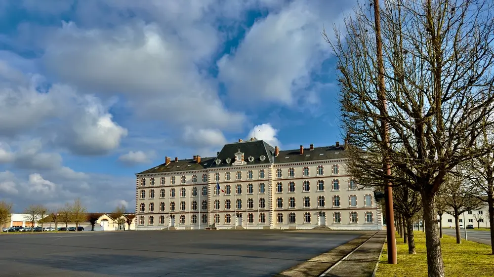 Bâtiment militaire d'une école de gendarmerie nationale avec drapeau tricolore et vaste place d'armes.