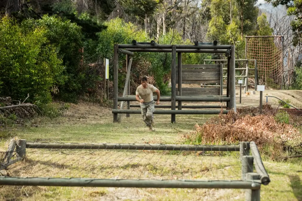 Un stagiaire en entraînement militaire court sur un parcours d'obstacles extérieur pour la réserve de la gendarmerie.