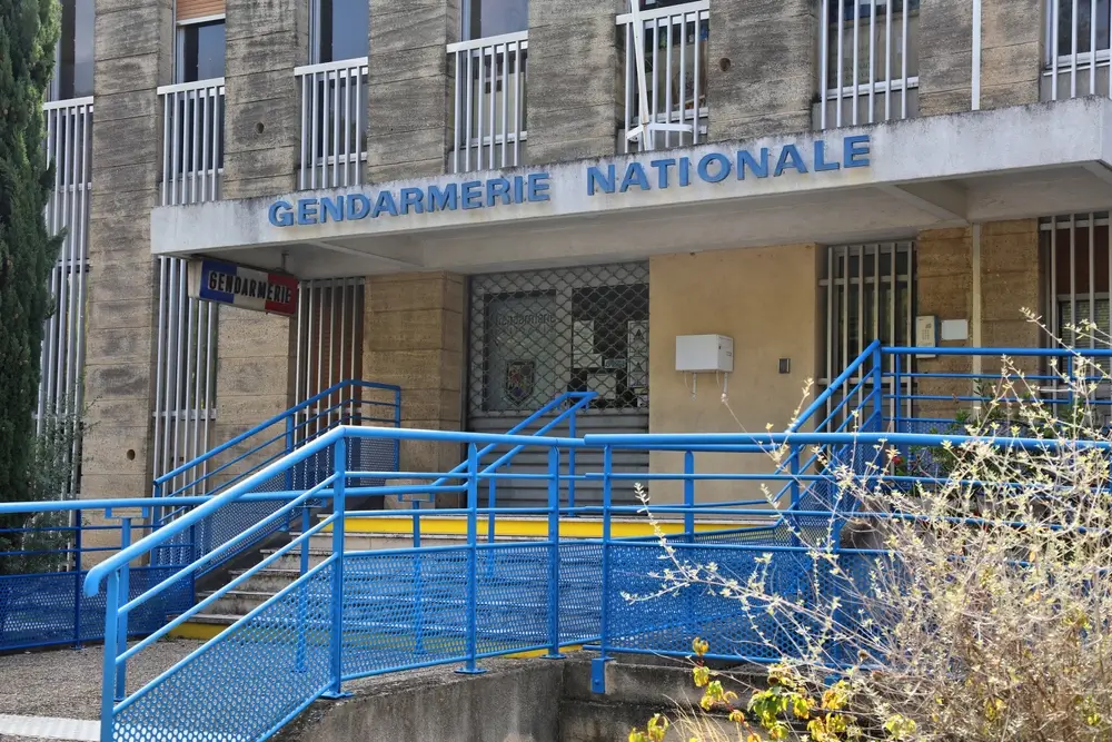 Entrée d'une brigade de gendarmerie nationale avec rampes d'accès bleues et enseigne officielle sur la façade.