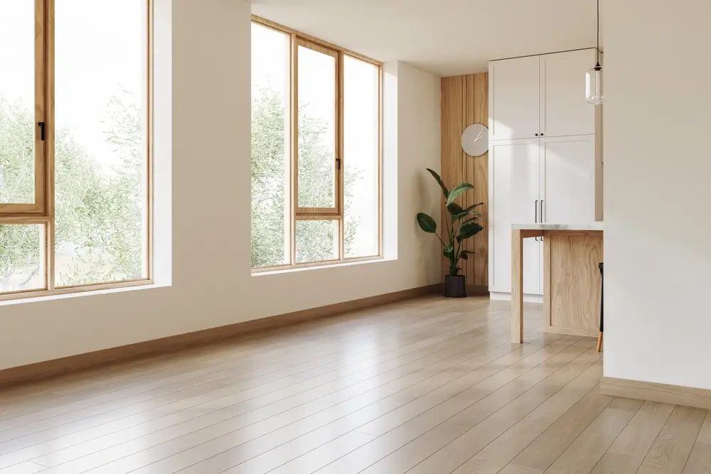 Intérieur moderne d'un logement de fonction militaire lumineux avec parquet clair, grandes fenêtres et coin cuisine.