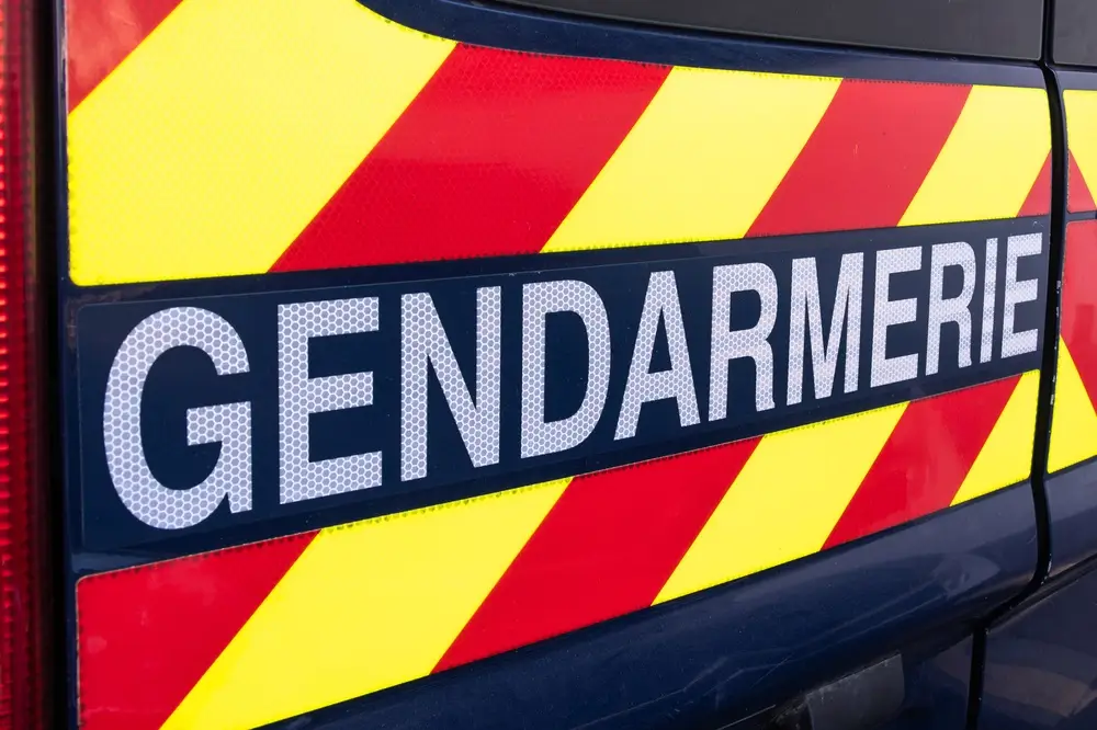 Véhicule de patrouille d'une brigade de gendarmerie avec logo blanc et bandes de signalisation rouges et jaunes.