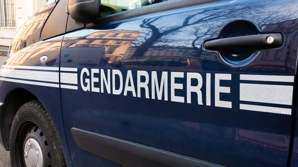 Véhicule de gendarmerie bleu avec marquages blancs et bandes réfléchissantes pour les missions de patrouille.