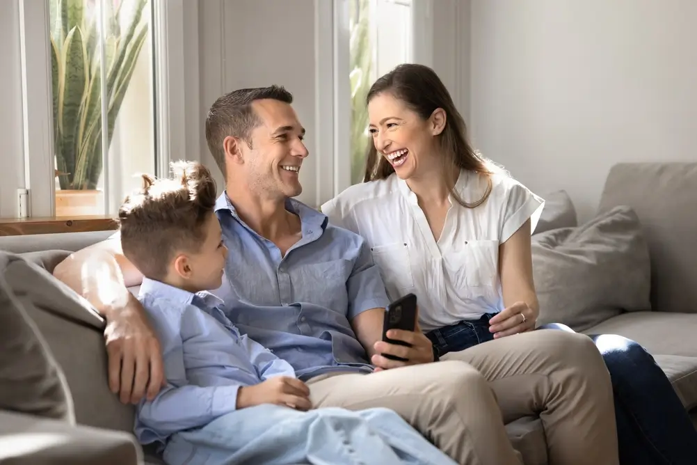 Famille heureuse partageant un moment complice dans le salon de leur appartement.