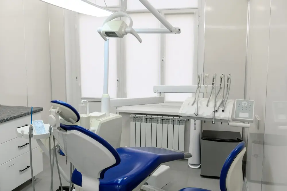 Fauteuil dentaire bleu et instruments de soin dans un cabinet dentaire moderne pour des soins courants.