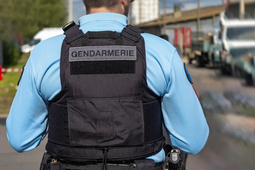 Officier de gendarmerie de dos en patrouille, portant un gilet tactique lors d'une mission de sécurité.