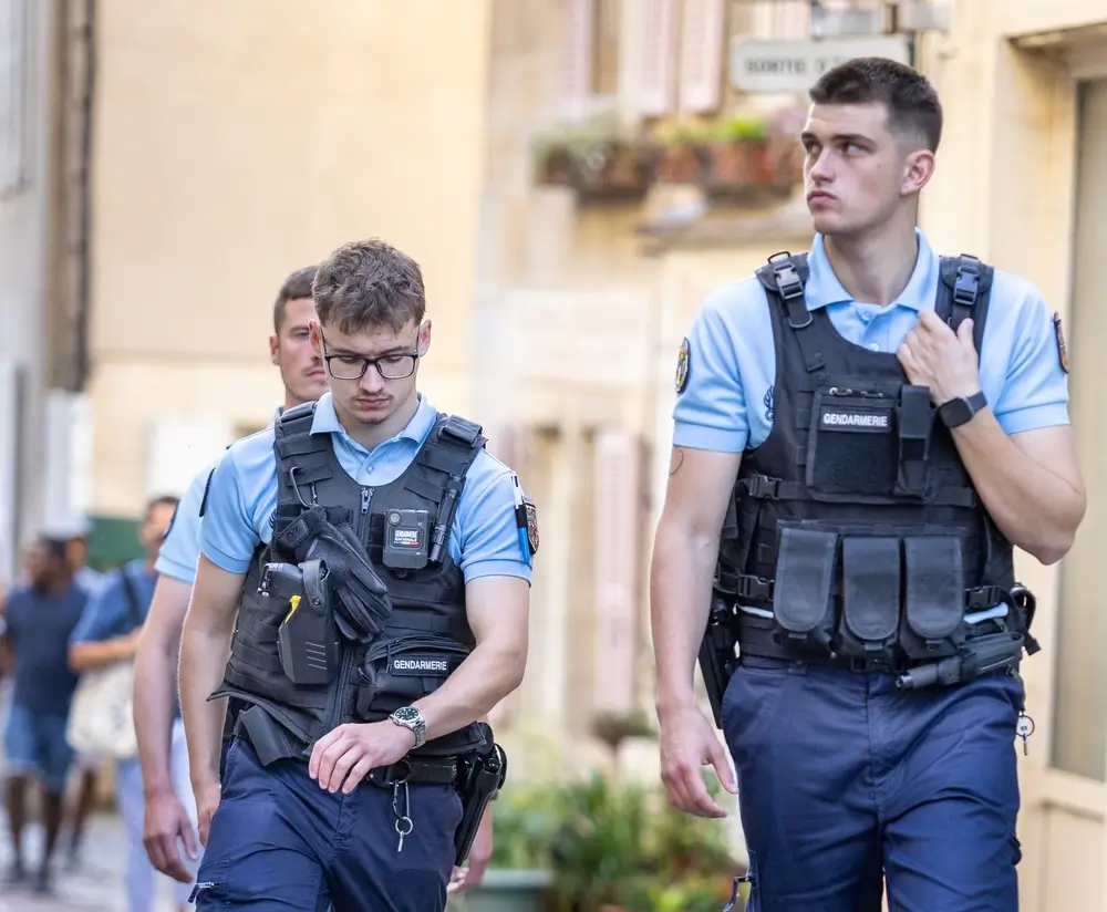 Patrouille de gendarmes en uniforme et gilets tactiques marchant dans une rue pour la sécurité publique.