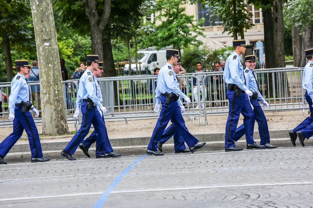 Gendarmes en uniforme marchant en ligne, illustrant la hiérarchie et les différents grades militaires.