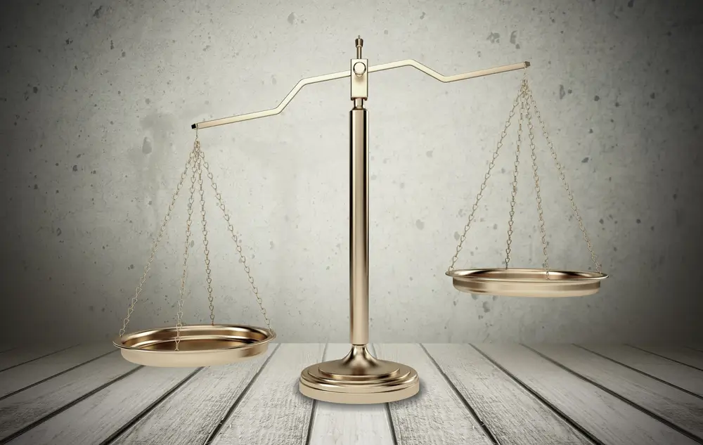 Balance de la justice dorée sur un sol en bois, symbolisant l'autorité judiciaire du gendarme OPJ.
