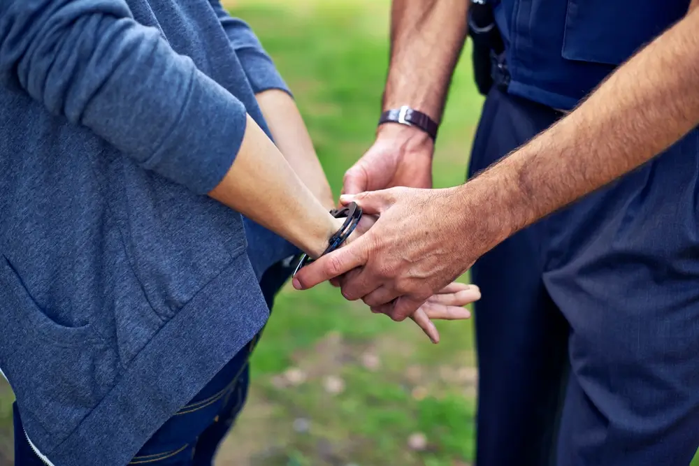 Gendarme en uniforme procédant au menottage d'un suspect lors d'une interpellation judiciaire.
