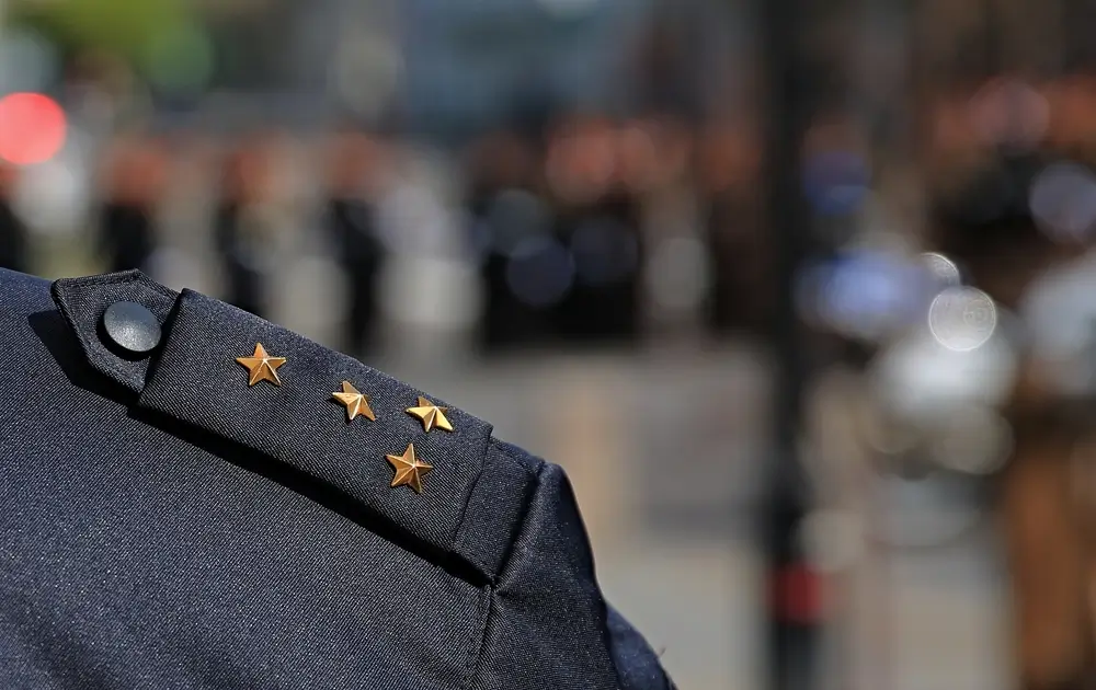 Insigne de grade militaire à quatre étoiles dorées fixé sur l'épaulette d'un uniforme bleu de gendarme.