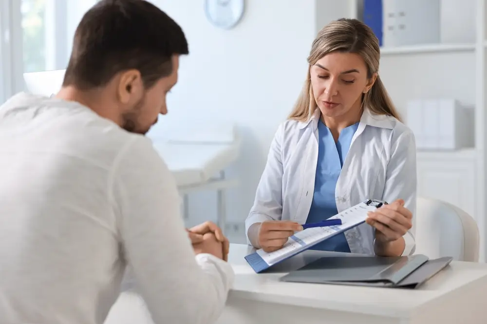 Médecin de famille expliquant un dossier de soins à son patient lors d'une visite et consultation médicale.