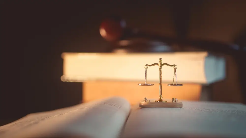 Balance de la justice dorée sur un livre de droit ouvert, symbolisant la formation juridique des officiers à l'AMGN.