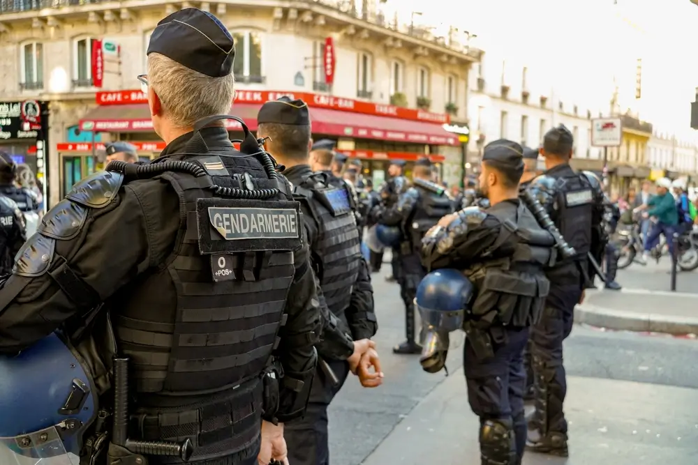 Gendarmes mobiles de dos en tenue de maintien de l'ordre avec casques et gilets de protection lors d'une intervention.