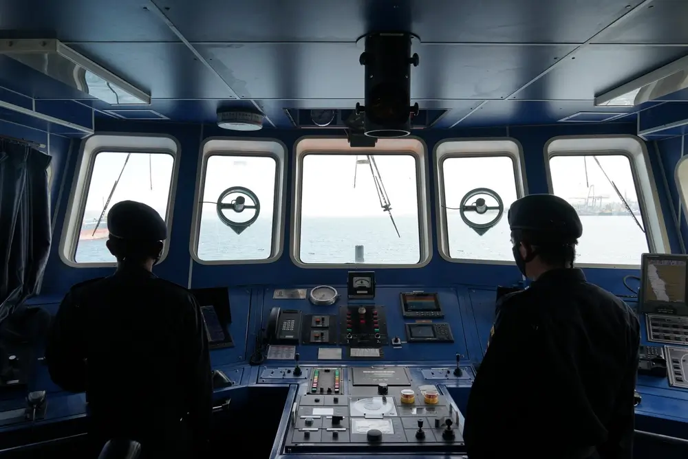 Deux gendarmes maritimes scrutent l'horizon depuis la passerelle d'un navire lors d'une patrouille de contrôle en mer.