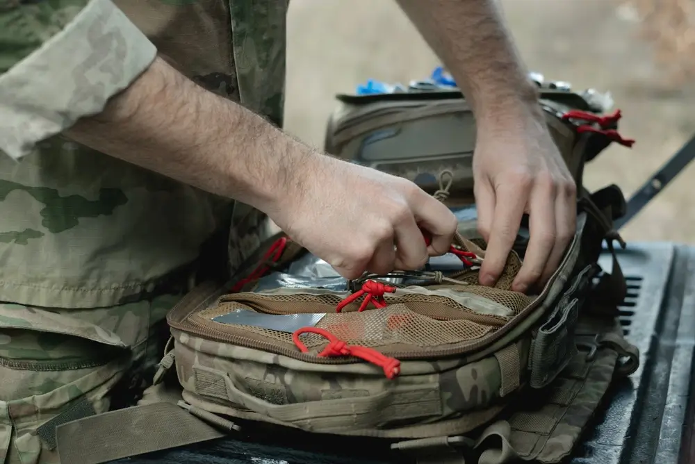 Médecin militaire préparant son sac de secours tactique pour prodiguer les premiers soins sur le terrain.