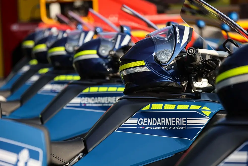Alignement de motos de la gendarmerie nationale garées avec les casques bleus des motocyclistes posés sur les réservoirs.