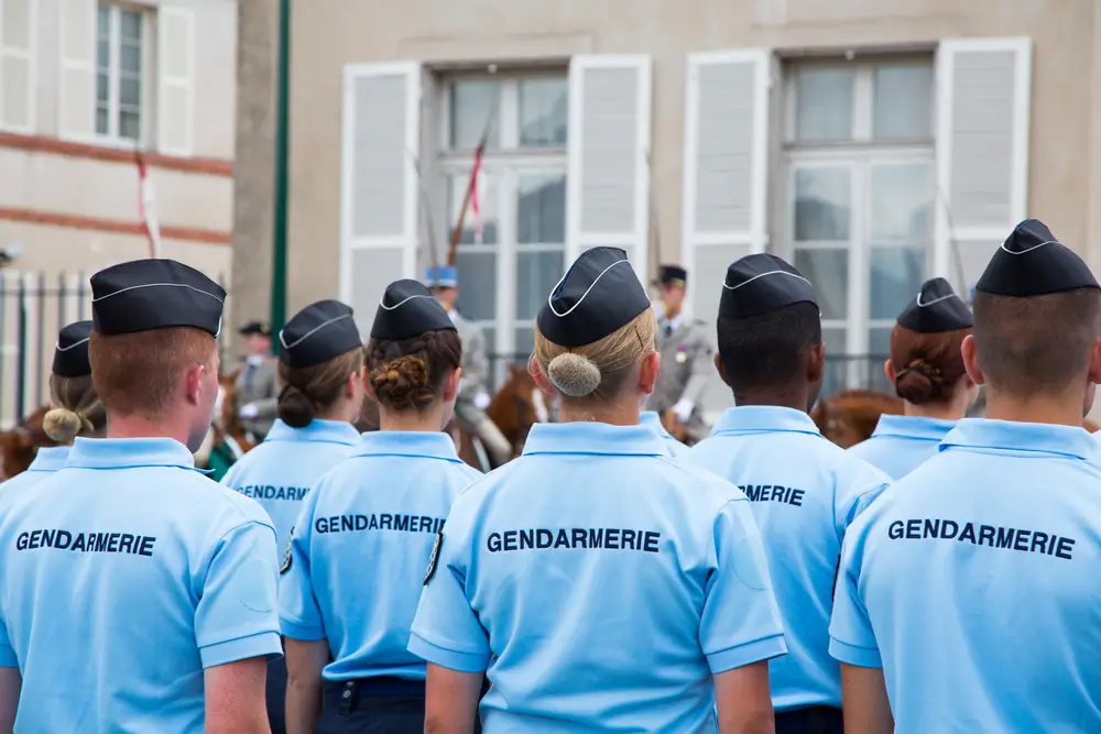 Sous-officiers de gendarmerie en tenue de service bleue devant un bâtiment de brigade territoriale française.